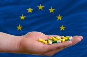 holding pills in hand in front of europe national flag