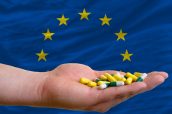 man holding capsules in front of complete wavy national flag of europe symbolizing health, medicine, cure, vitamines and healthy life