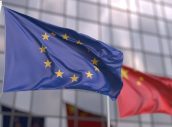 Waving flags of the European Union EU and China in front of a modern skyscraper facade. 3D rendering