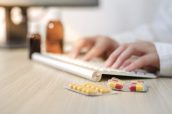 Female doctor writing prescription, closeup of hands typing. On the side pills and bottles with medication