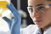 Chemist girl looks at flask with yellow liquid