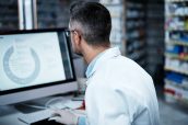 Getting hands on in the discovery of new medicines. a mature man using a computer while working in a pharmacy.