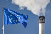 Waving European flag in front of a polluting factory chimney with smoke