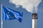 Waving European flag in front of a polluting factory chimney with smoke