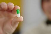 Mature hispanic woman holding pill at home