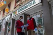 Voluntarios de Cruz Roja planificando la entrega de medicamentos a domicilio junto a una farmacia de Valencia.