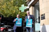 De izda. a dcha. Josean Fernández, presidente de Aergi; y Miguel Ángel Gastelurrutia, presidente del COFG, con los carteles informativos que se colocarán en las farmacias de Gipuzkoa.